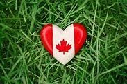 Stone heart with a canadian flag painted on it laying on grass to represent Canada Day