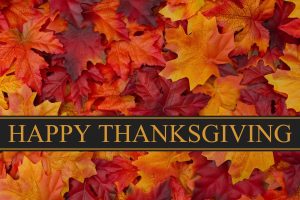 A background of Red, yellow and orange leaves with a black and gold banner that says "Happy Thanksgiving"